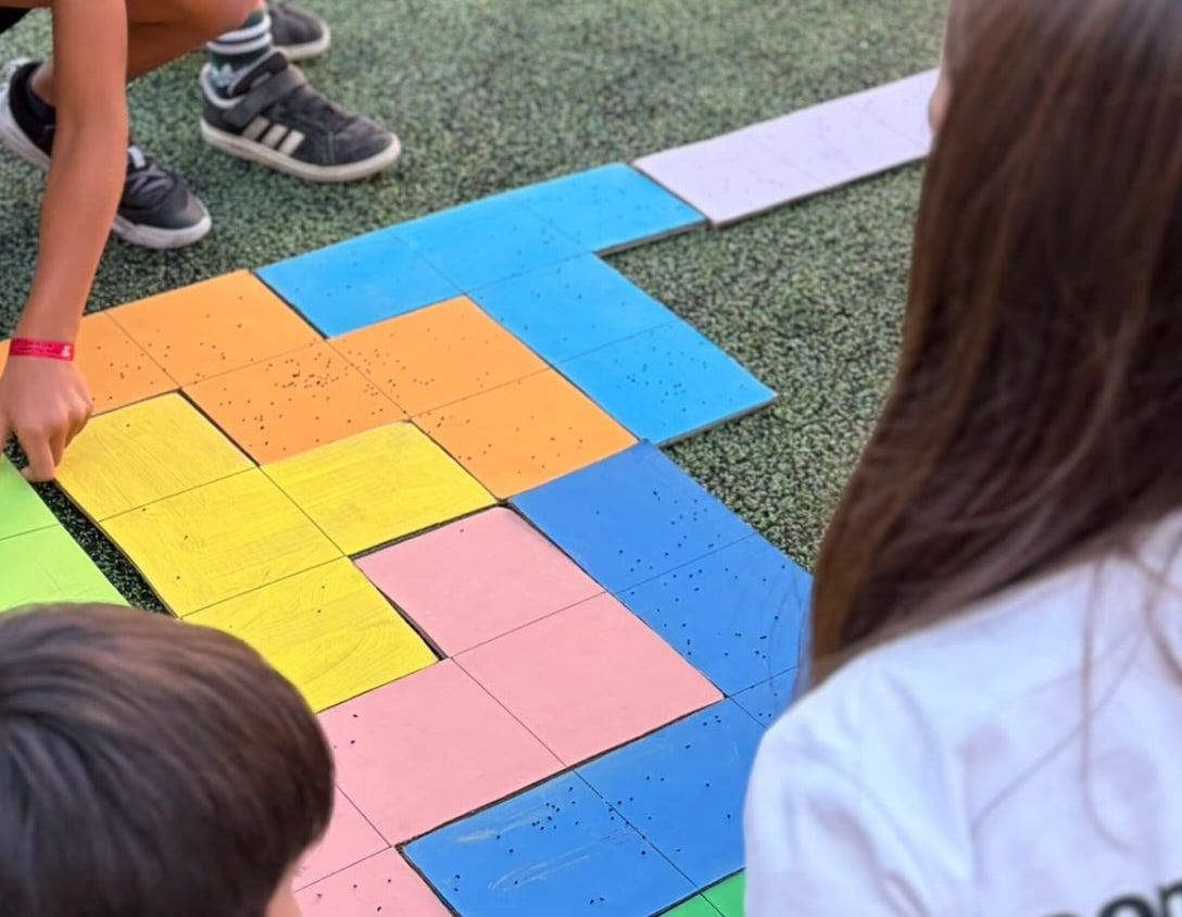 Alunos do 1.º Ciclo a montar um puzzle gigante de matemática no relvado