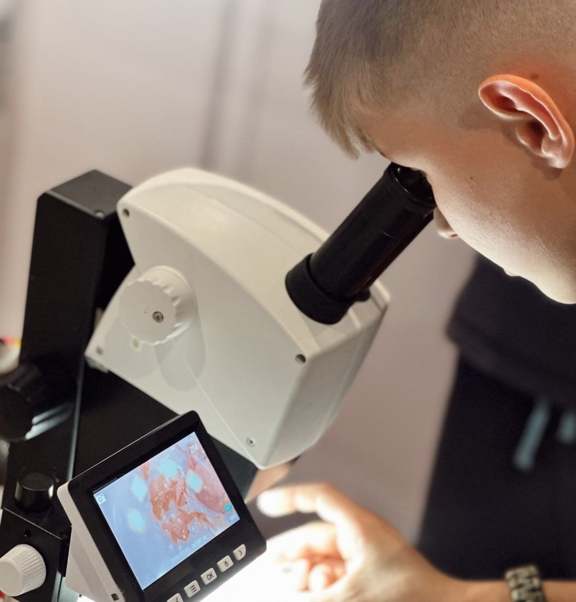 A 2nd Cycle pupil looking at a sample under a digital microscope